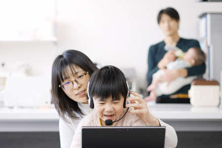 Asian female disturbed by children's teleworkの写真素材