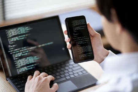 Asian programmer checking the operation of the codeの写真素材