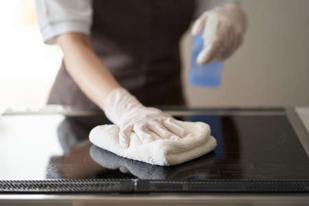 Asian woman cleaning an IH cooking heater