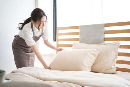 Asian woman making a bed in the bedroomの写真素材