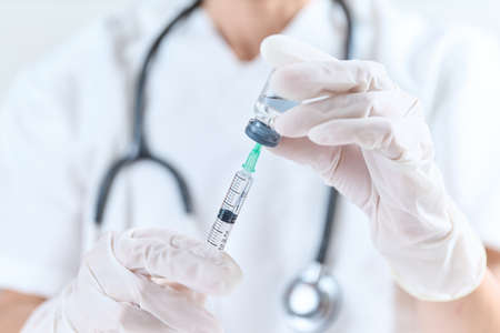 Doctor sucking an injection drug from a vial bottleの写真素材