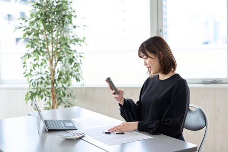 Asian woman filing tax return on smartphoneの写真素材
