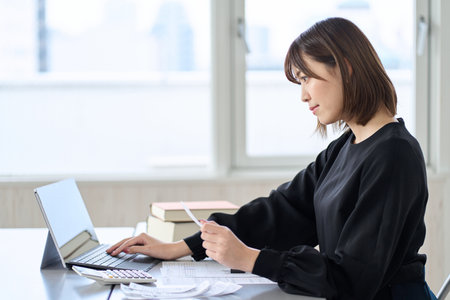 Asian woman entering expenses in accounting softwareの写真素材