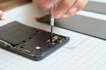Hands performing disassembly maintenance of smartphonesの写真素材