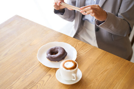 Asian woman taking a photo at a cafeの写真素材