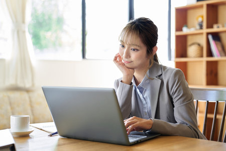 An Asian woman operating a computer with a troublesome lookの写真素材