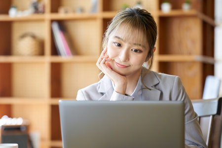 An Asian woman operating a computer with a troublesome lookの写真素材
