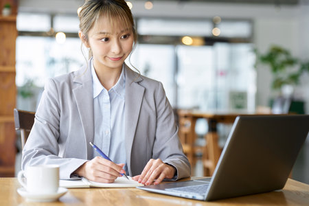 Asian woman studying using a computer at a cafeの写真素材