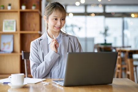 A woman having an online meeting at a cafeの写真素材
