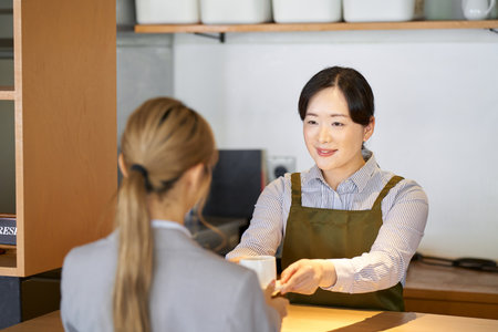 Cafe worker passing coffee over the counterの写真素材