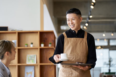 Asian male clerk working at a cafeの写真素材