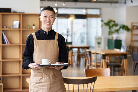 Male employee of a restaurant standing inside the storeの写真素材