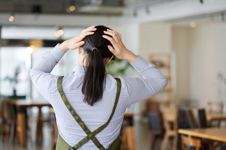 A female employee of a restaurant who is worried about managementの写真素材