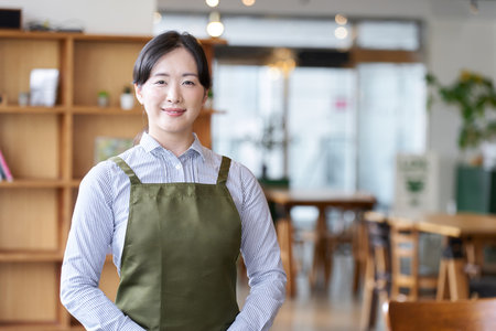 A female restaurant employee standing inside the storeの写真素材
