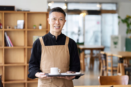 Male employee of a restaurant standing inside the storeの写真素材
