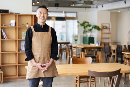 Male employee of a restaurant standing inside the storeの写真素材