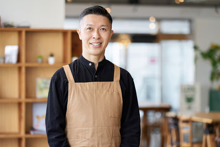 Male employee of a restaurant standing inside the storeの写真素材