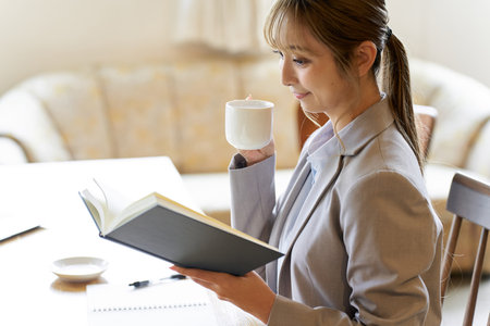 Business woman reading while drinking coffeeの写真素材