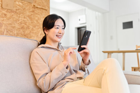 Asian woman sending a message on smartphoneの写真素材