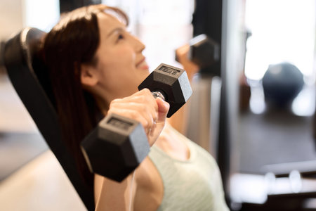 Woman training her chest with dumbbell pressesの写真素材