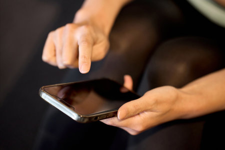 A woman managing her gym using a smartphone appの写真素材