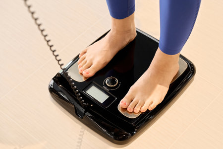 A woman using a body fat scale at the gymの写真素材