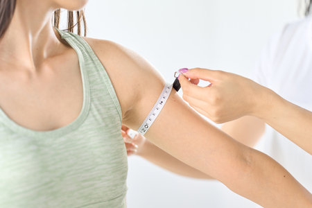 A woman measuring the circumference of her arm with a tape measureの写真素材