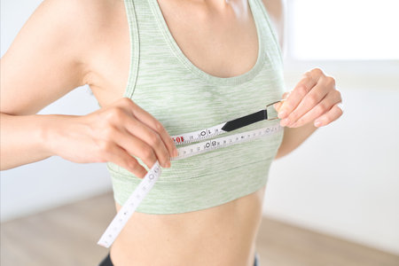 A woman measuring her chest circumference with a measuring tapeの写真素材