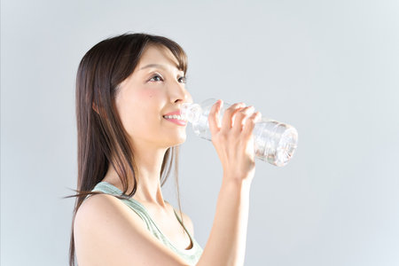 A woman drinking water from a plastic bottleの写真素材