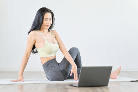 A woman stretches while watching a videoの写真素材