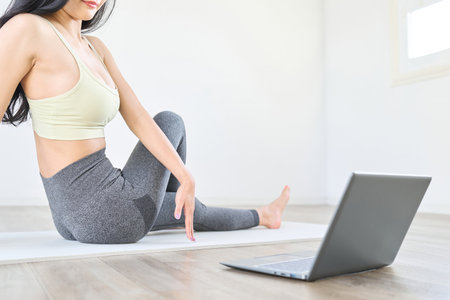 A woman stretches while watching a videoの写真素材
