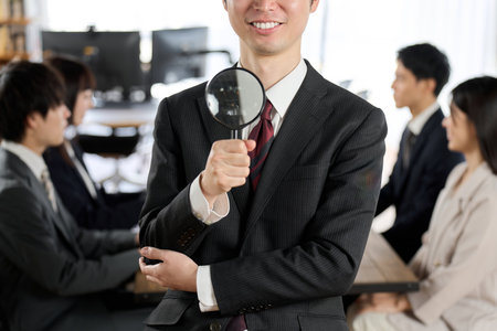 Asian businessman with magnifying glassの写真素材