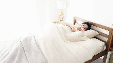 A man measures his temperature with a thermometer while sleepingの写真素材