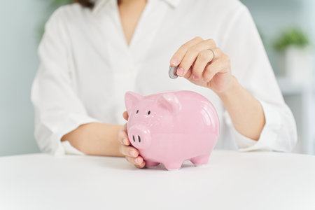 A woman putting money into a pig piggy bankの写真素材