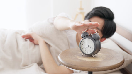 A man stops a ringing alarm clockの写真素材