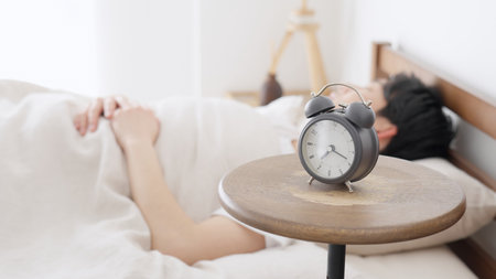 A man sets an alarm clock and sleepsの写真素材