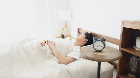 A man sets an alarm clock and sleepsの写真素材