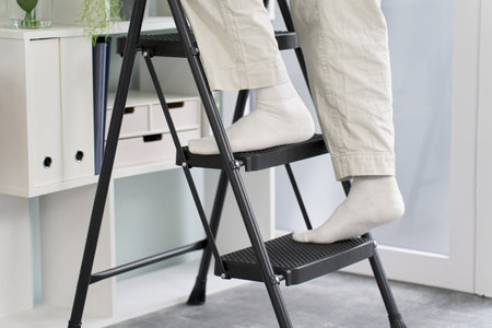 The feet of a man on a stepladder tidying things upの写真素材