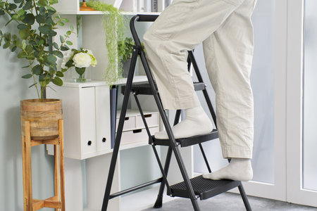 The feet of a man on a stepladder tidying things upの写真素材