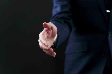 Businessman asking for a handshake on black backgroundの写真素材