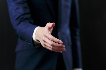 Businessman asking for a handshake on black backgroundの写真素材