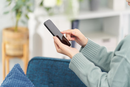 A woman operating a smartphone in the living roomの写真素材