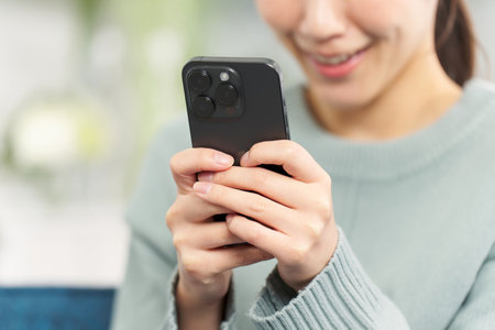 A woman operating a smartphone in the living roomの写真素材