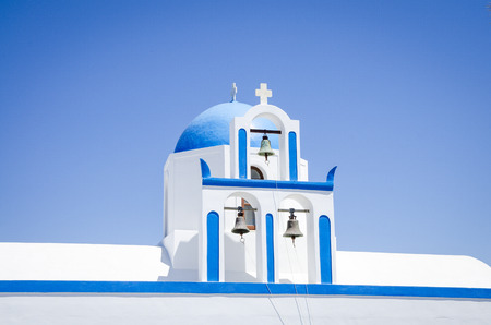 On the road of oia a little church with a blue dome and three bellsの写真素材