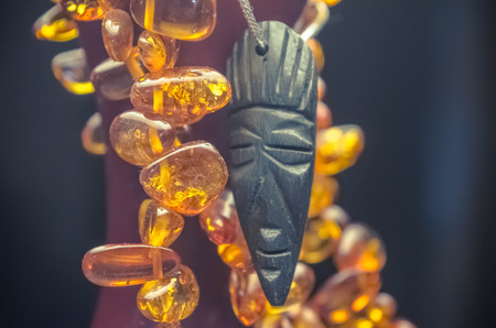 African tribal mask with an amber necklace at the dark background.の写真素材