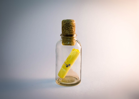 Message in a glowing bottle sealed with a cork at a deep blue background.の写真素材