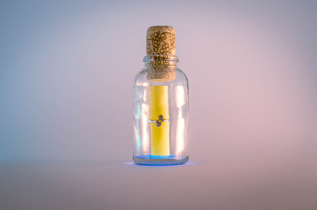 Message in a glowing bottle sealed with a cork at a light background.の写真素材