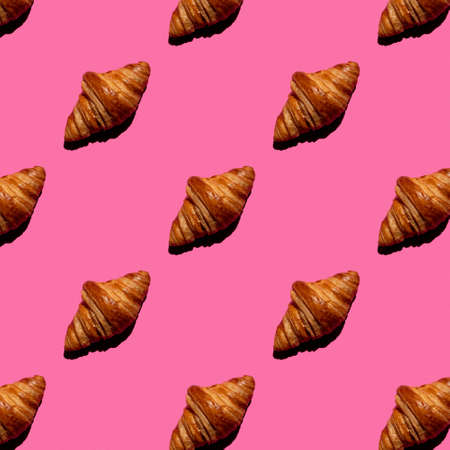 seamless pattern of tasty croissant on a pink background with hard lightの写真素材