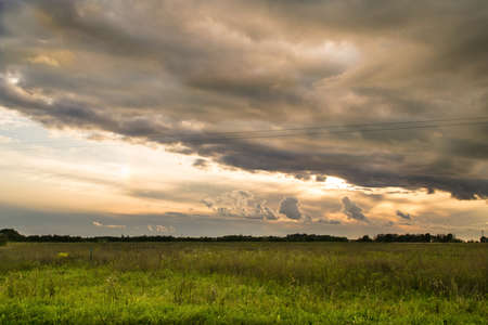 Cloudy sunset landscape in a countryside fieldの写真素材