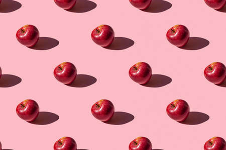 seamless pattern of a photo of a ripe red apple on a pink backgroundの写真素材